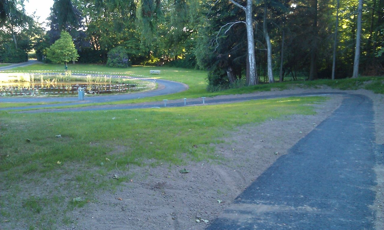 Asfaltsti, park og lille sø